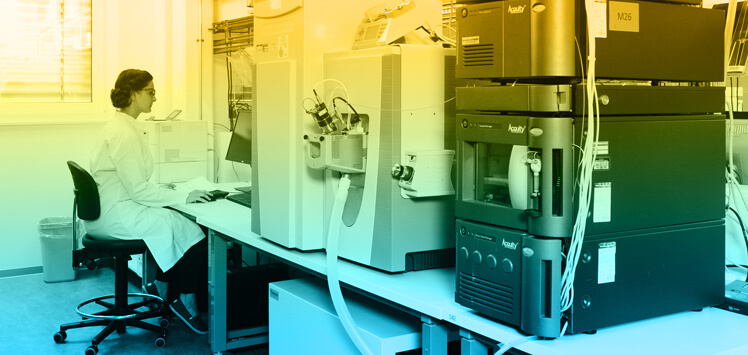 Frau im Chemielabor vor Analysegeräten